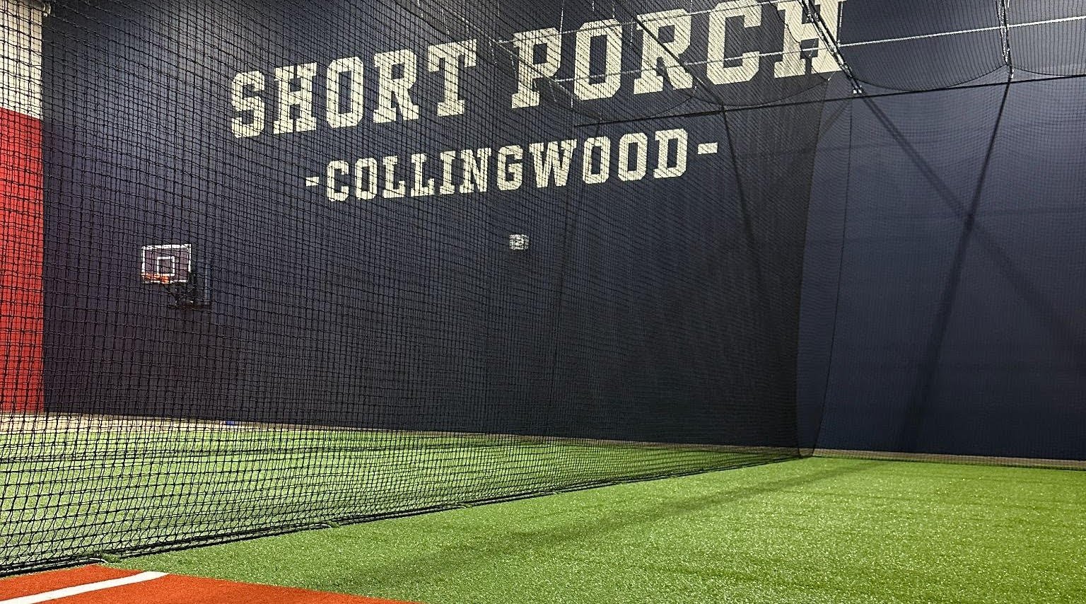 Inside the Short Porch Baseball facility in Collingwood — cage netting, turf, and SHORT PORCH COLLINGWOOD branding